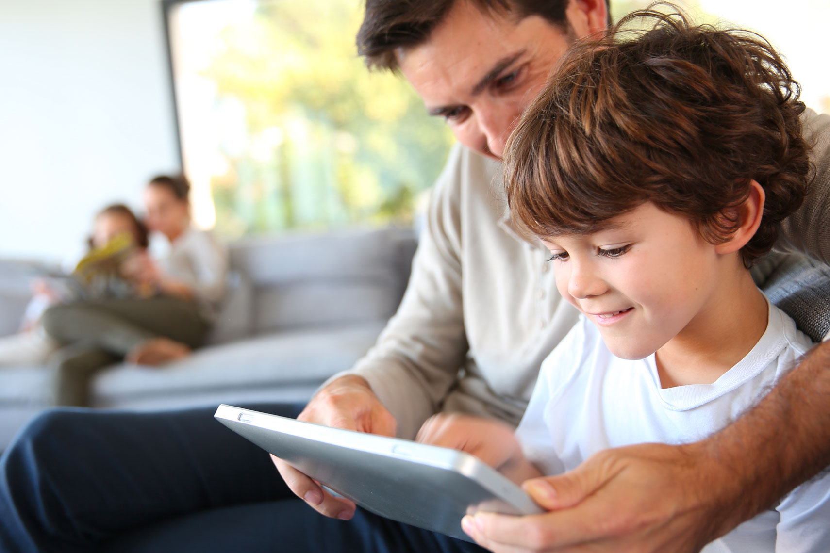 Padre e figlio sul divano guardano il tablet